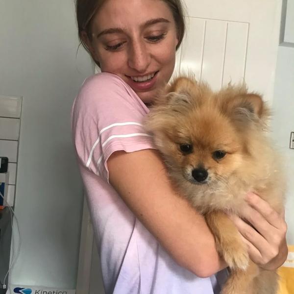 Charlotte cuddling a small fluffy golden dog